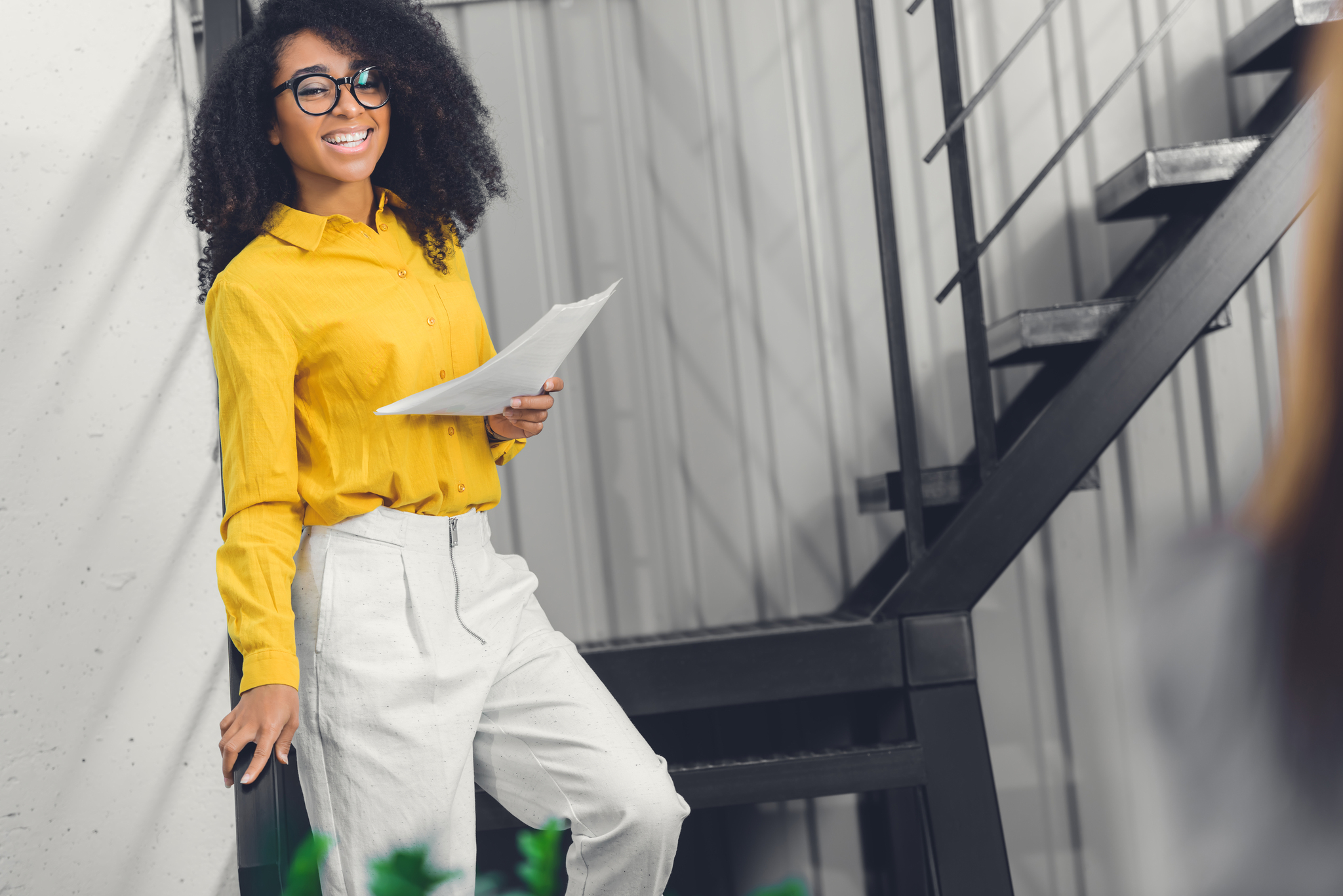 beautiful african american businesswoman holding papers and smiling at camera in office